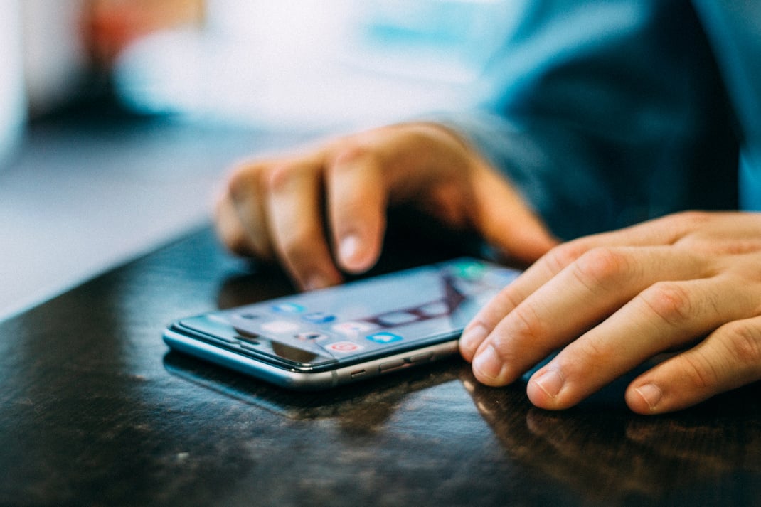 Person Holding Space Gray Iphone 6 on Tabe